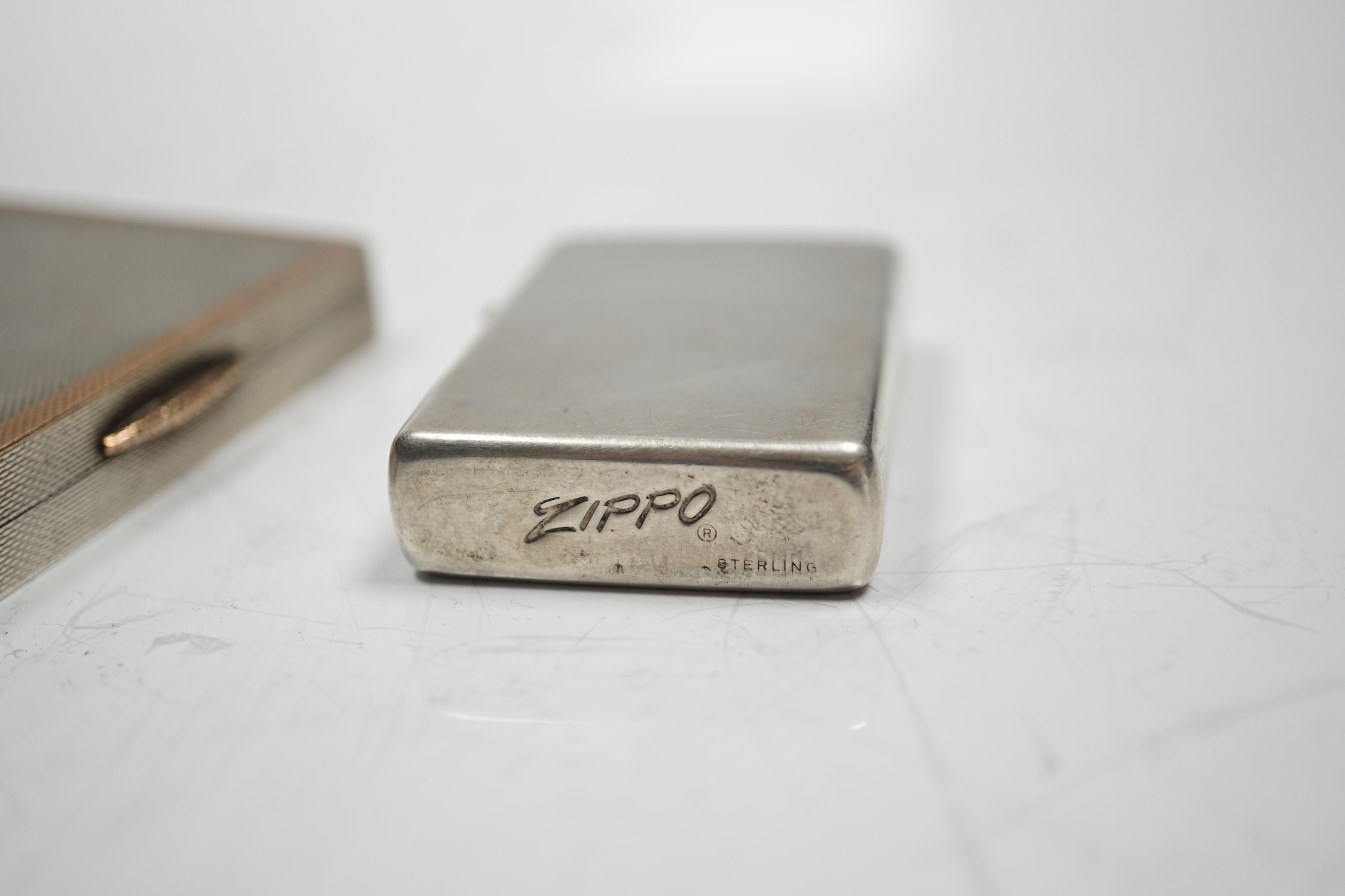A sterling cased Zippo lighter, 71mm, together with a 1930's engine turned silver cigarette case.